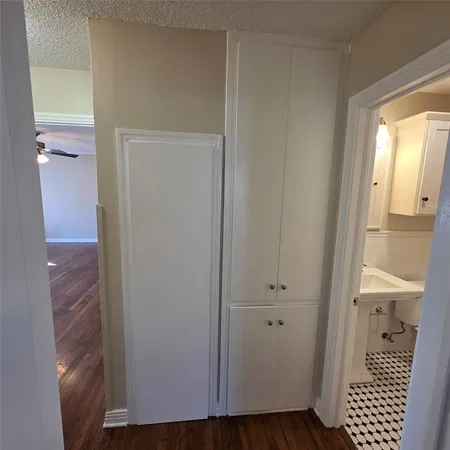a view of a hallway with wooden floor and a bathroom