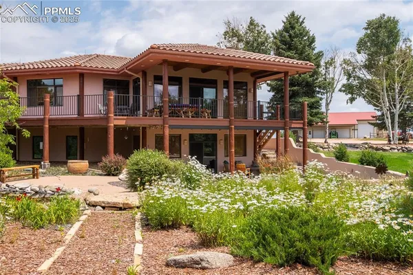 a front view of a house with a garden and trees