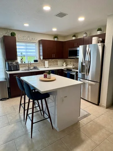 a kitchen with a sink a microwave a refrigerator and chairs