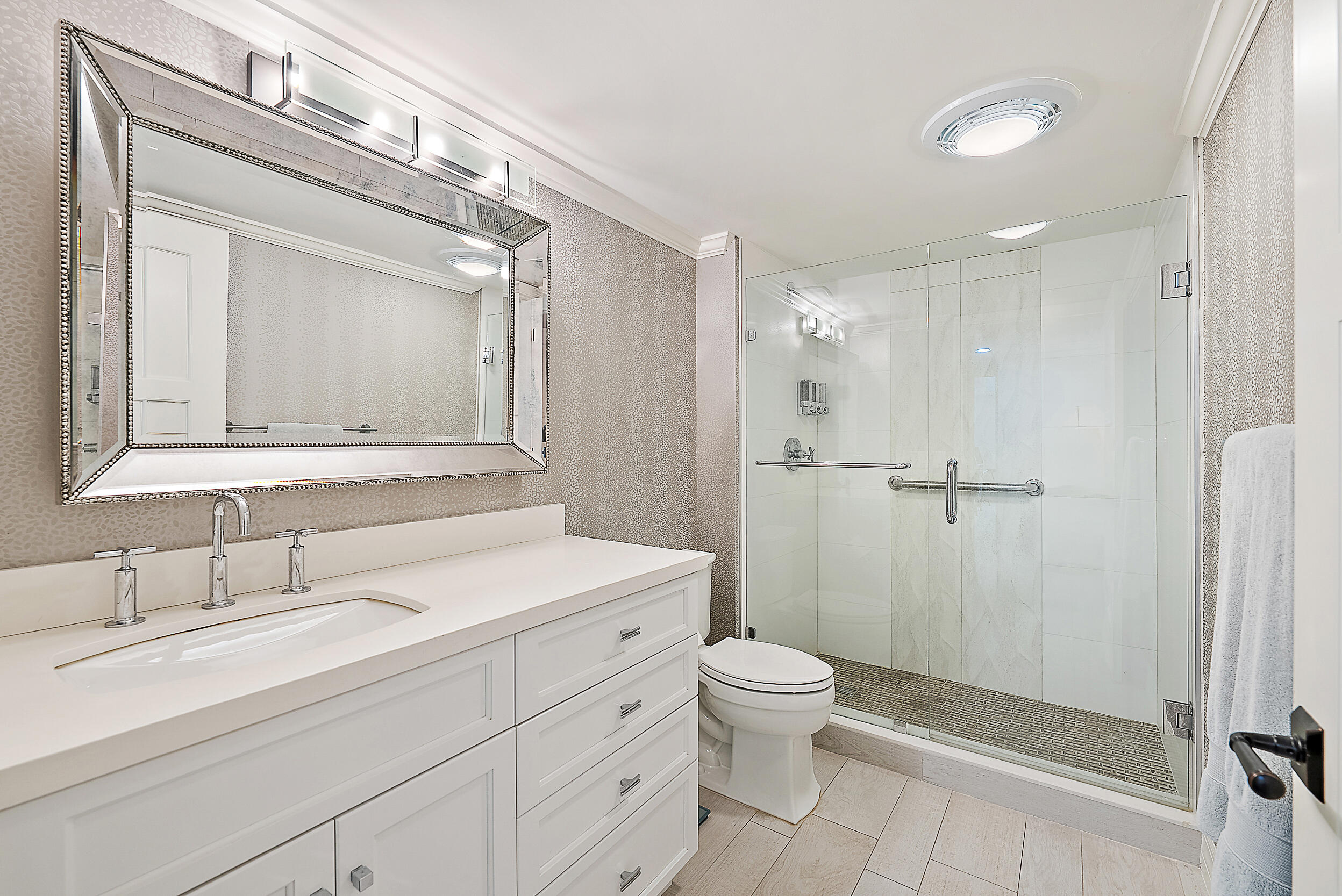 16648 Traders Crossing North, Unit 106 Jupiter, FL 33477 - Photo 17 of 37 a bathroom with a toilet a sink a mirror and vanity