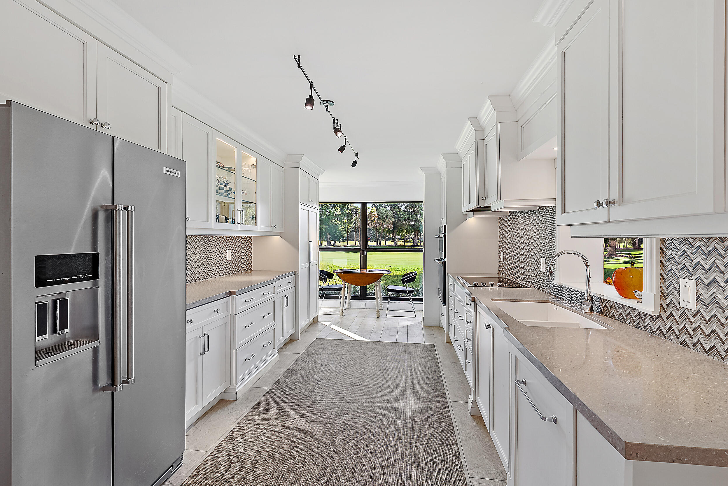 16648 Traders Crossing North, Unit 106 Jupiter, FL 33477 - Photo 4 of 37 a kitchen with stainless steel appliances granite countertop a refrigerator a sink dishwasher a oven and white cabinets with wooden floor