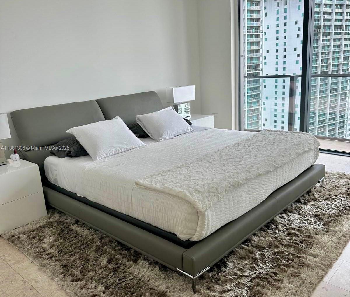 68 Southeast 6th Street, Unit 2801 Miami, FL 33131 - Photo 8 of 10 a large bed sitting in a bedroom next to a window