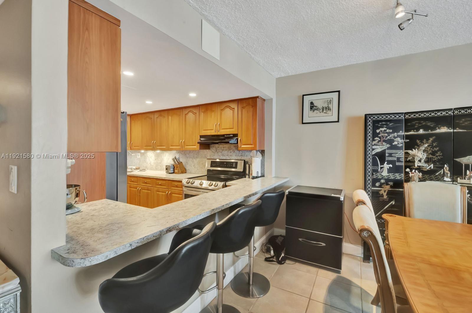 5401 Collins Avenue, Unit 340 Miami Beach, FL 33140 - Photo 51 of 54 a kitchen with a table chairs sink and stove