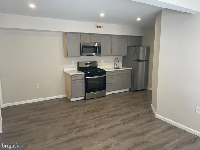 a kitchen with a sink a stove top oven and white stainless steel appliances