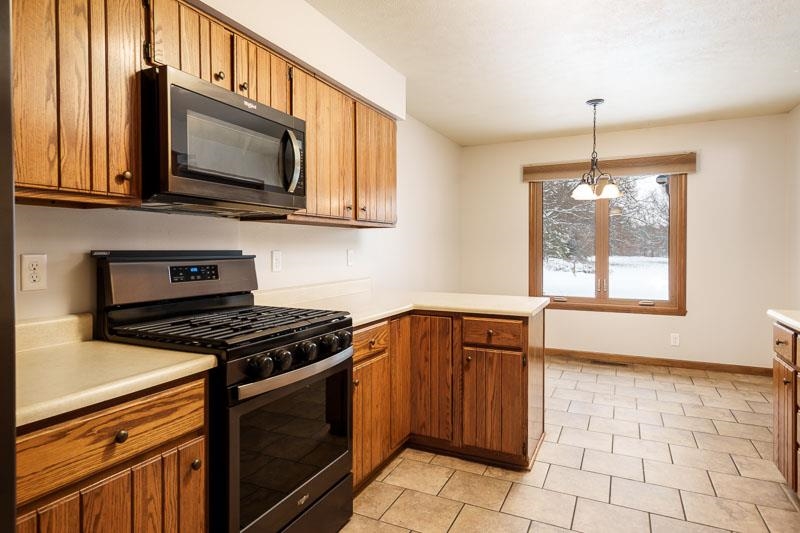10077 Jesters Row Roscoe, IL 61073 - Photo 16 of 61 a kitchen with stainless steel appliances granite countertop a stove a sink and a microwave