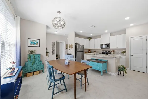 a open dining room with stainless steel appliances kitchen island a table and chairs in it