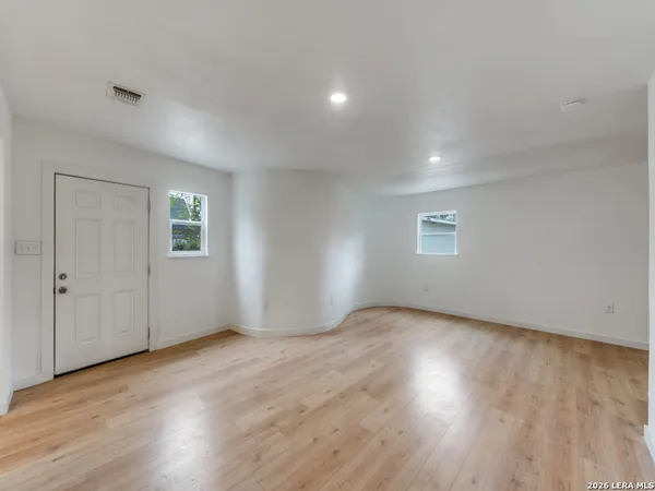 an empty room with wooden floor and windows