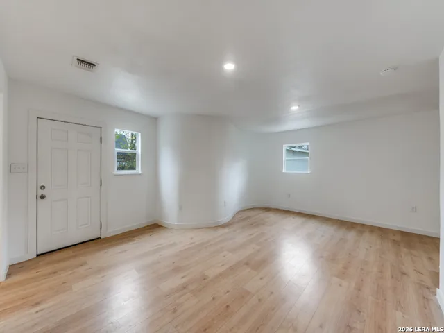 an empty room with wooden floor and windows