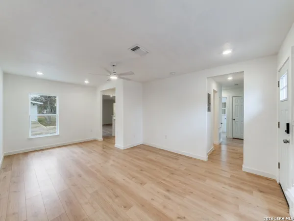 a view of an empty room with wooden floor and a window