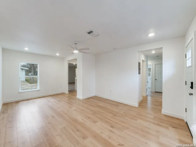 a view of an empty room with wooden floor and a window