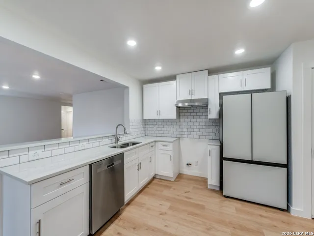 a kitchen with a sink a refrigerator and a stove top oven