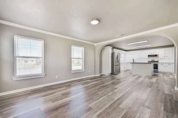 an empty room with wooden floor and windows