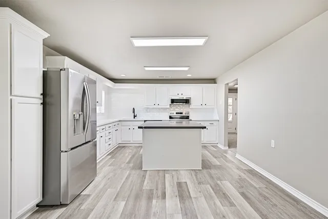 a kitchen with white cabinets and stainless steel appliances