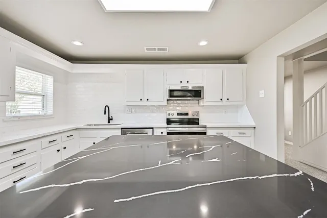 a kitchen with granite countertop a stove a sink and a refrigerator
