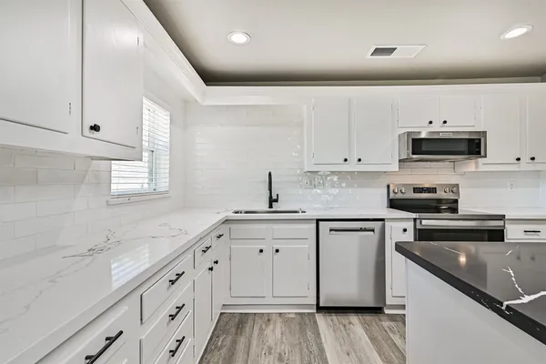 a kitchen with granite countertop white cabinets and white appliances