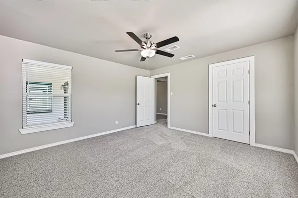 a view of an empty room with a ceiling fan and a window
