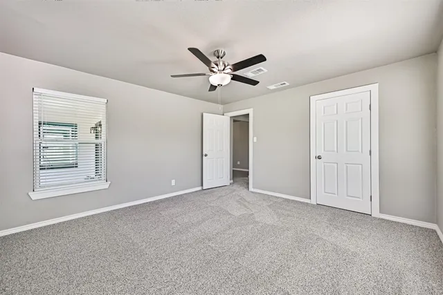 a view of an empty room with a ceiling fan and a window