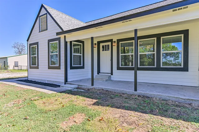 a view of a house with small yard plants and wooden fence