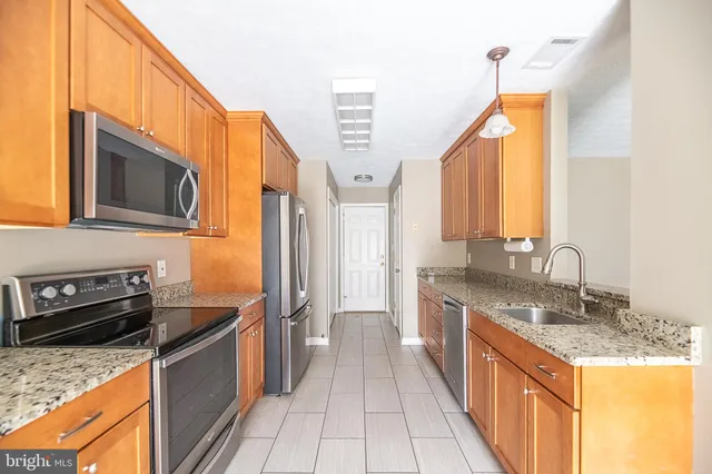 a kitchen with stainless steel appliances granite countertop a stove a sink and a microwave