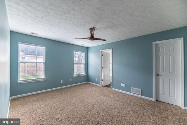 an empty room with windows and ceiling fan
