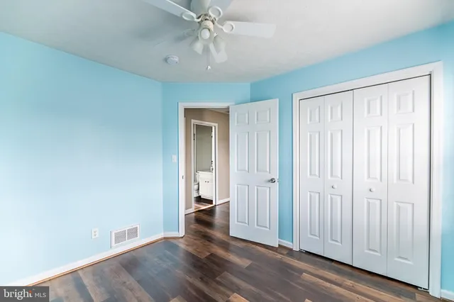 an empty room with wooden floor cabinet and windows