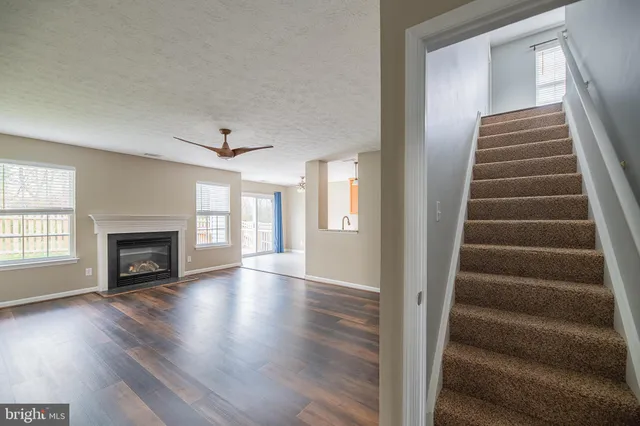 a view of an empty room with wooden floor fireplace and windows
