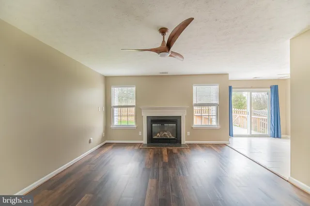 an empty room with wooden floor fireplace and windows