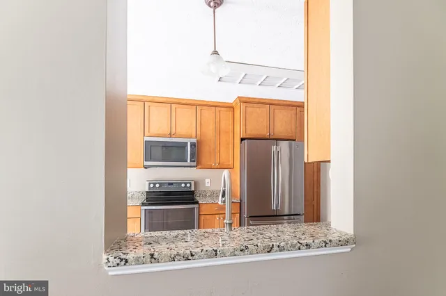 a kitchen with granite countertop a refrigerator and a stove top oven