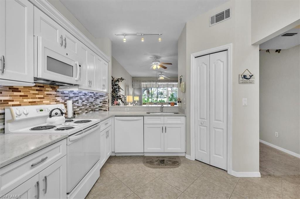 8075 Tiger Cove, Unit 1706 Naples, FL 34113 - Photo 11 of 50 Kitchen featuring white appliances, white cabinets, light tile patterned floors, decorative backsplash, and ceiling fan