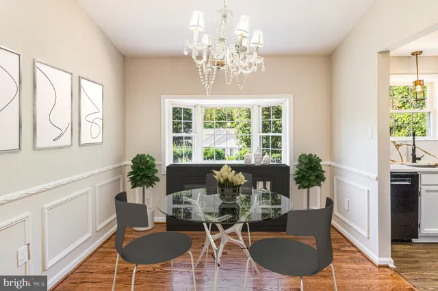 a dining room with wooden floor a chandelier a glass table and chairs