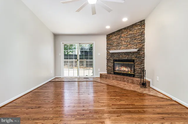 a view of an empty room with wooden floor fireplace and a window