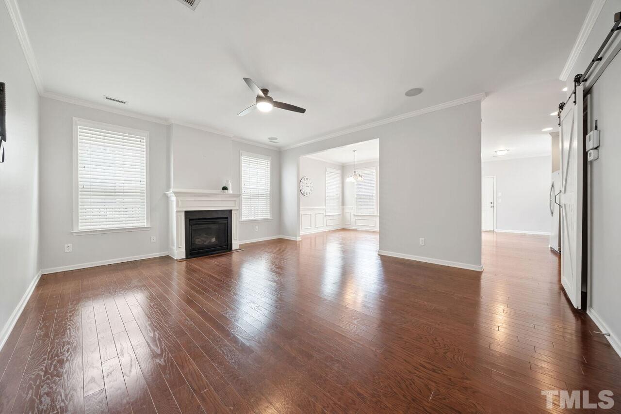 1026 Ileagnes Road Raleigh, NC 27603 - Photo 7 of 29 an empty room with wooden floor fireplace and windows