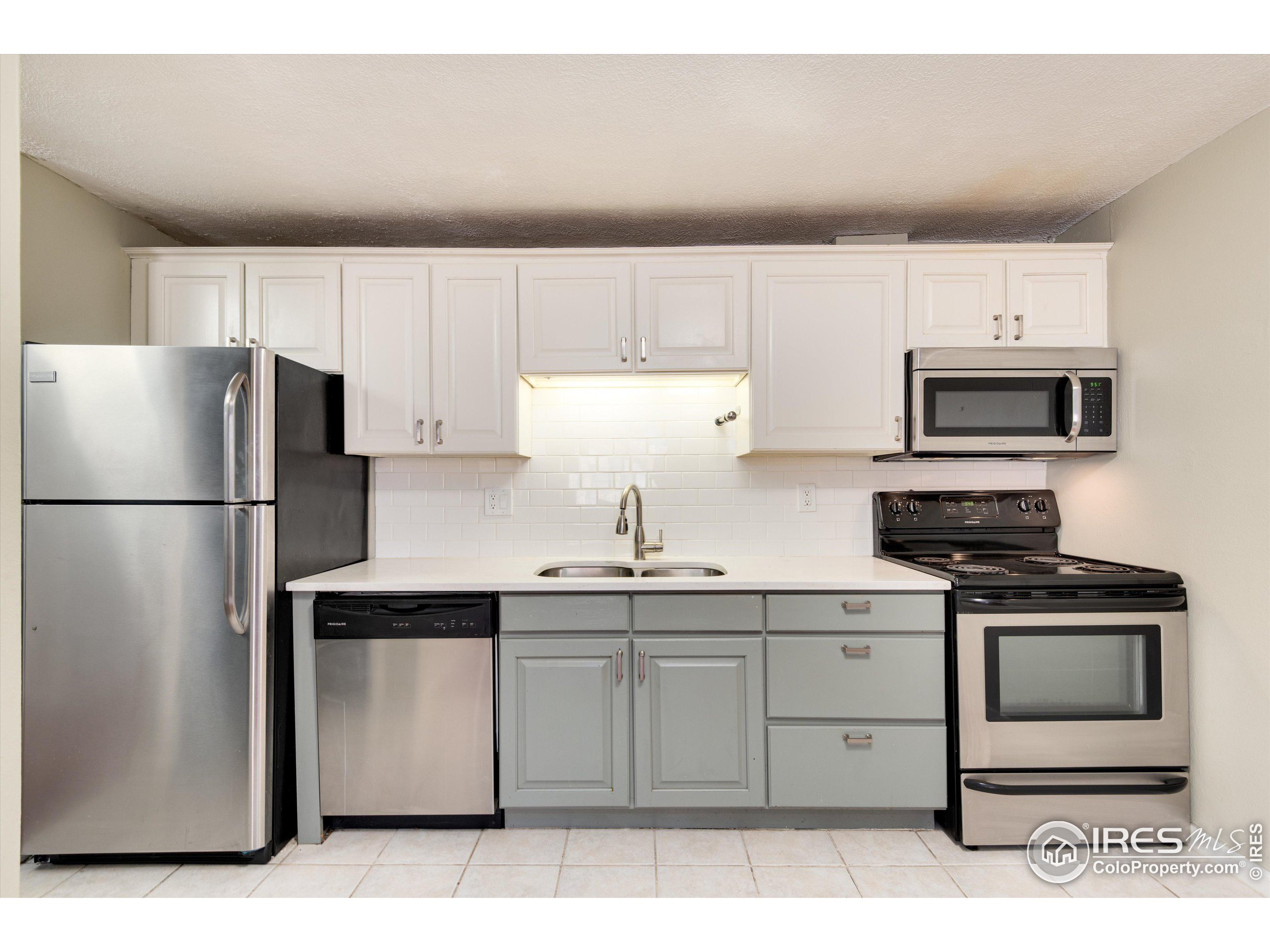 a kitchen with stainless steel appliances white cabinets sink and a refrigerator