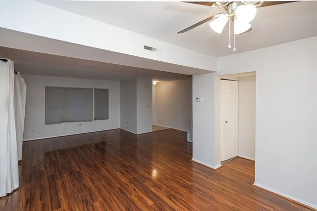 a view of an empty room with wooden floor and a chandelier