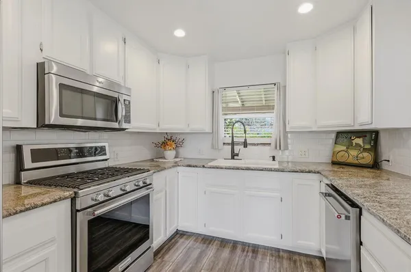 a kitchen with granite countertop cabinets stainless steel appliances a sink and wooden floor