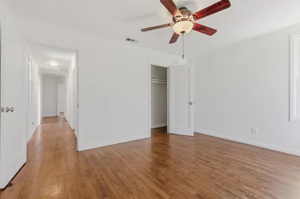 a view of an empty room with window and wooden floor
