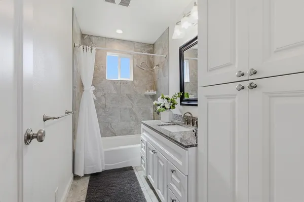 a bathroom with a granite countertop sink a toilet and shower