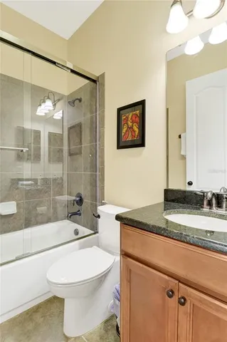 a bathroom with a granite countertop toilet a sink and a mirror