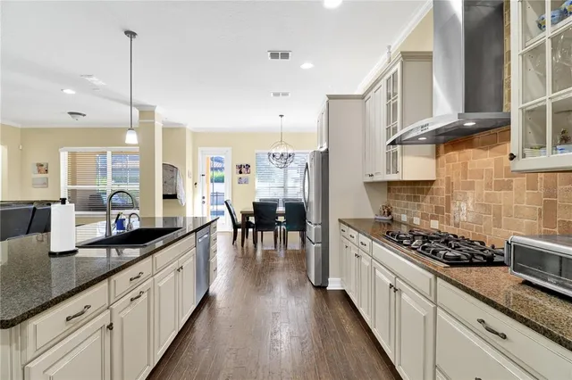 a kitchen with stainless steel appliances kitchen island granite countertop a stove a sink and white cabinets