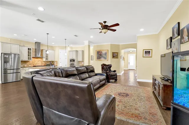 a living room with stainless steel appliances furniture a couch and a kitchen view