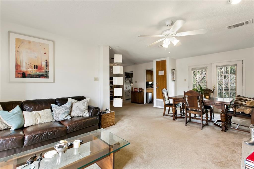 9201 Simmons Road, Unit 117 Austin, TX 78759 - Photo 5 of 11 Open-concept living and dining area featuring neutral carpeting and white wall finishes