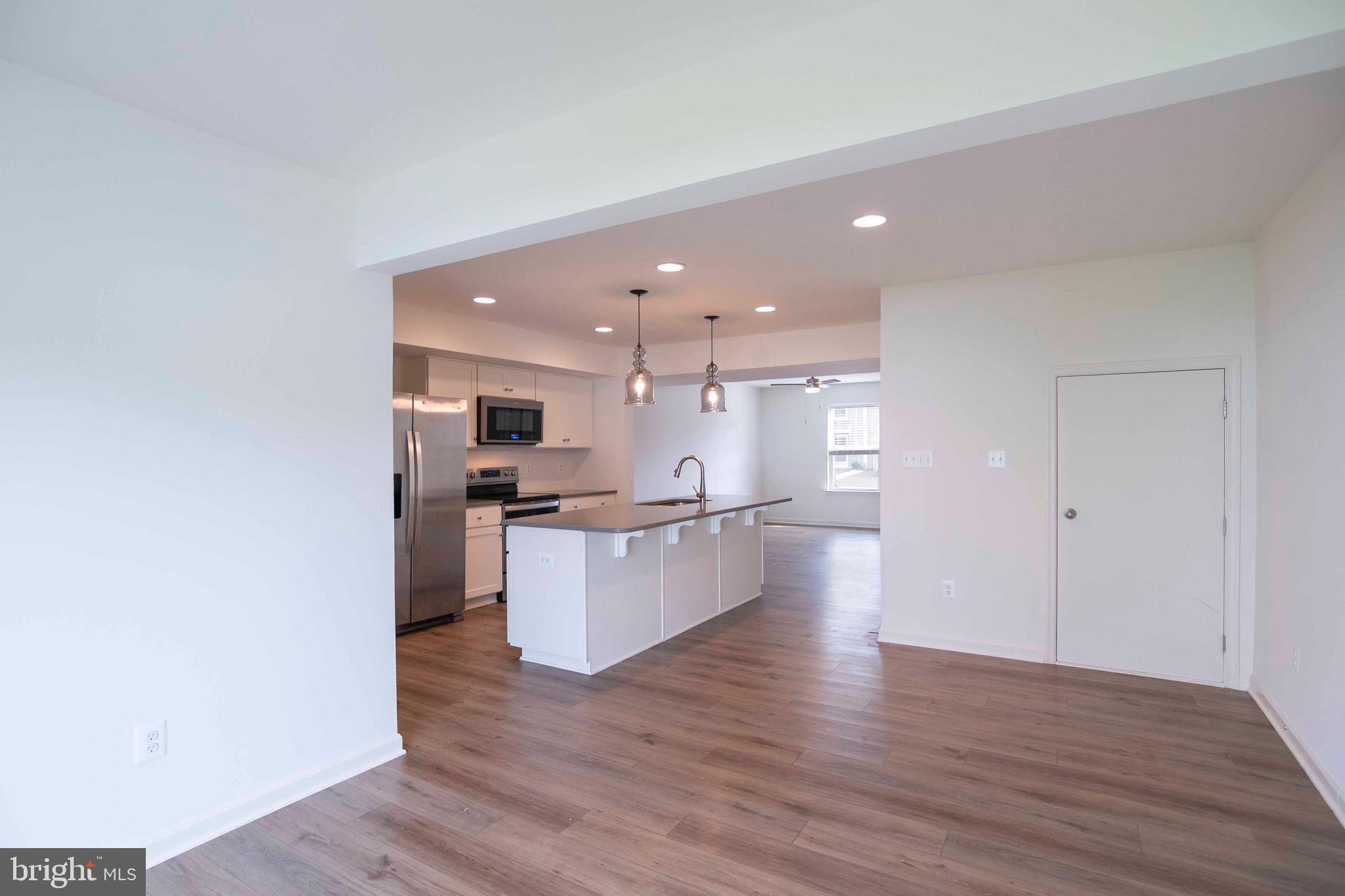 15 Pitch Pine Bunker Hill, WV 25413 - Photo 13 of 37 a large kitchen with kitchen island a sink dishwasher a refrigerator and a stove top oven with wooden floor