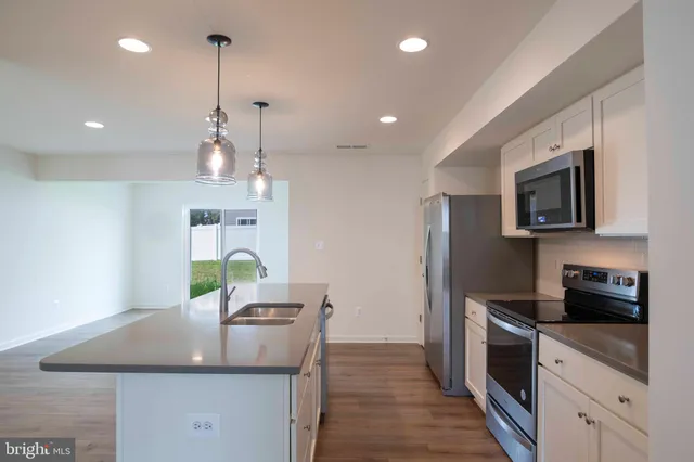 a kitchen with kitchen island granite countertop a sink a counter space appliances and cabinets