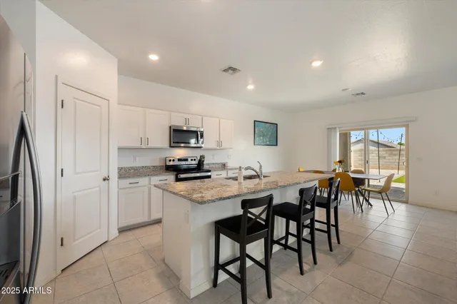 a kitchen with a sink a microwave a refrigerator and chairs