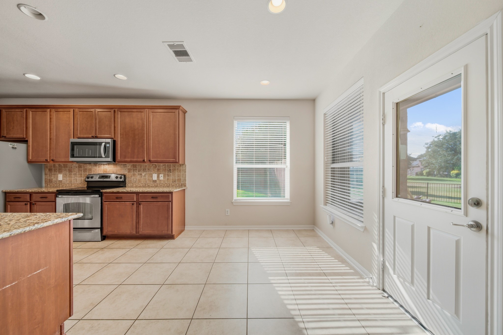 6015 Biltmore Court Rosenberg, TX 77471 - Photo 9 of 31 a large kitchen with stainless steel appliances granite countertop a stove a sink dishwasher a microwave oven and white cabinets with wooden floor