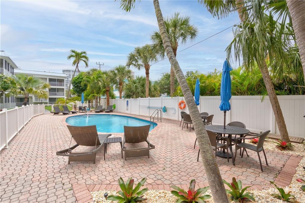 1439 South Ocean Boulevard, Unit 211 Pompano Beach, FL 33062 - Photo 15 of 46 a view of a patio with table and chairs potted plants and palm tree