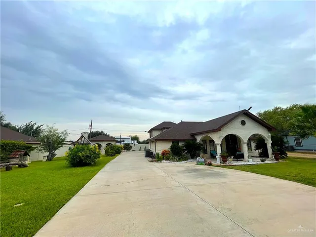 a view of a house with a big yard plants and large trees
