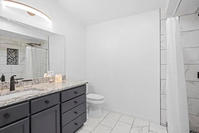 a bathroom with a granite countertop sink a toilet and a mirror