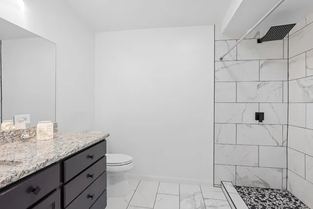 a bathroom with a granite countertop sink and a toilet