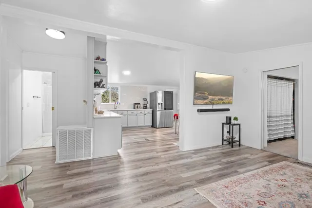 a view of living room kitchen with wooden floor and flat screen tv